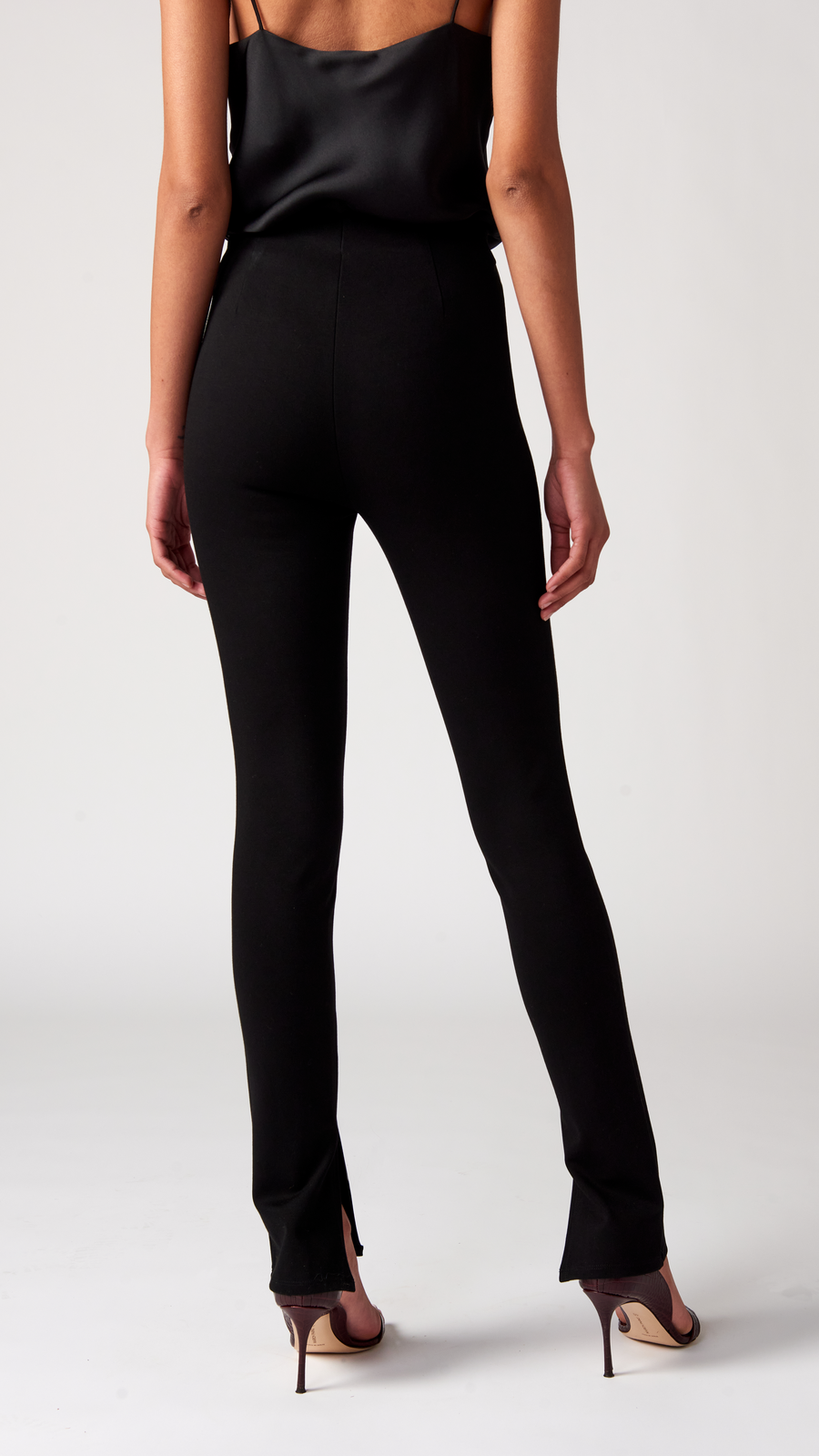 The back view of the black high-waisted pants on a woman.