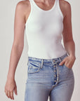 A woman wearing a white long rib tank body suit and paired it with a high-waisted denim jean.